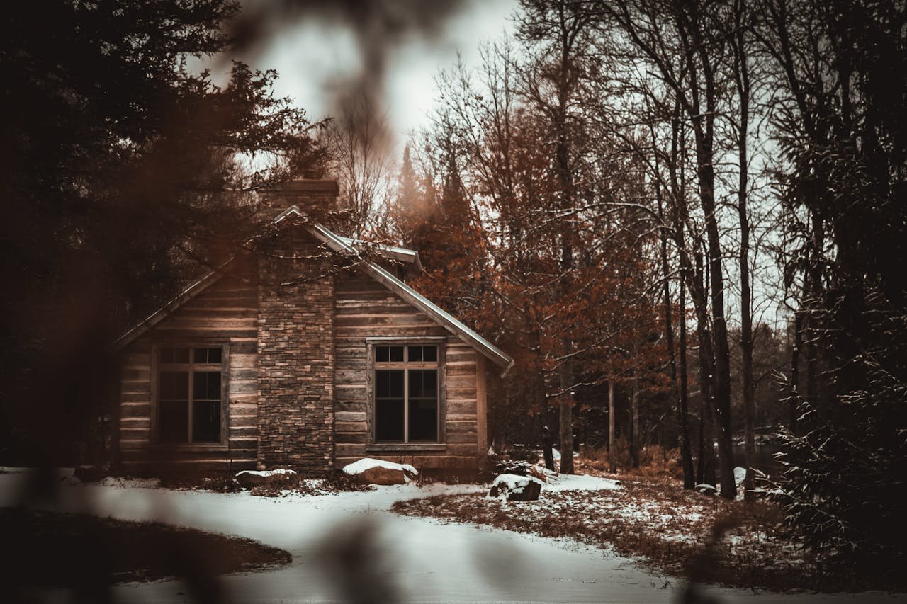 A serene log cabin surrounded by snowy trees, creating a cozy winter landscape.